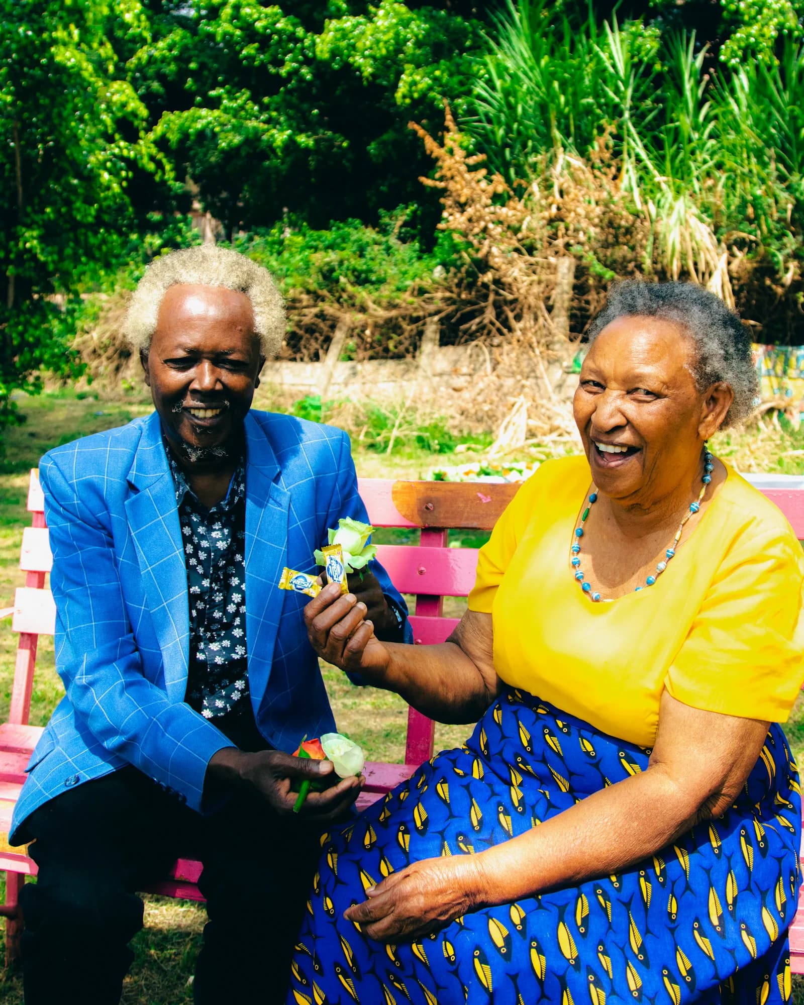 Two older Kenyan adults sharing a joyful moment outdoors.
